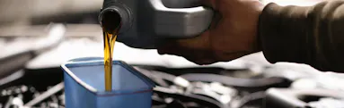 A Jiffy Lube technician replacing a vehicle's transmission fluid